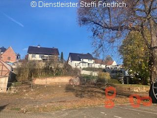 Blick leicht hangaufwärts über beräumtes Grundstück im Hintergrund weitere Häuser