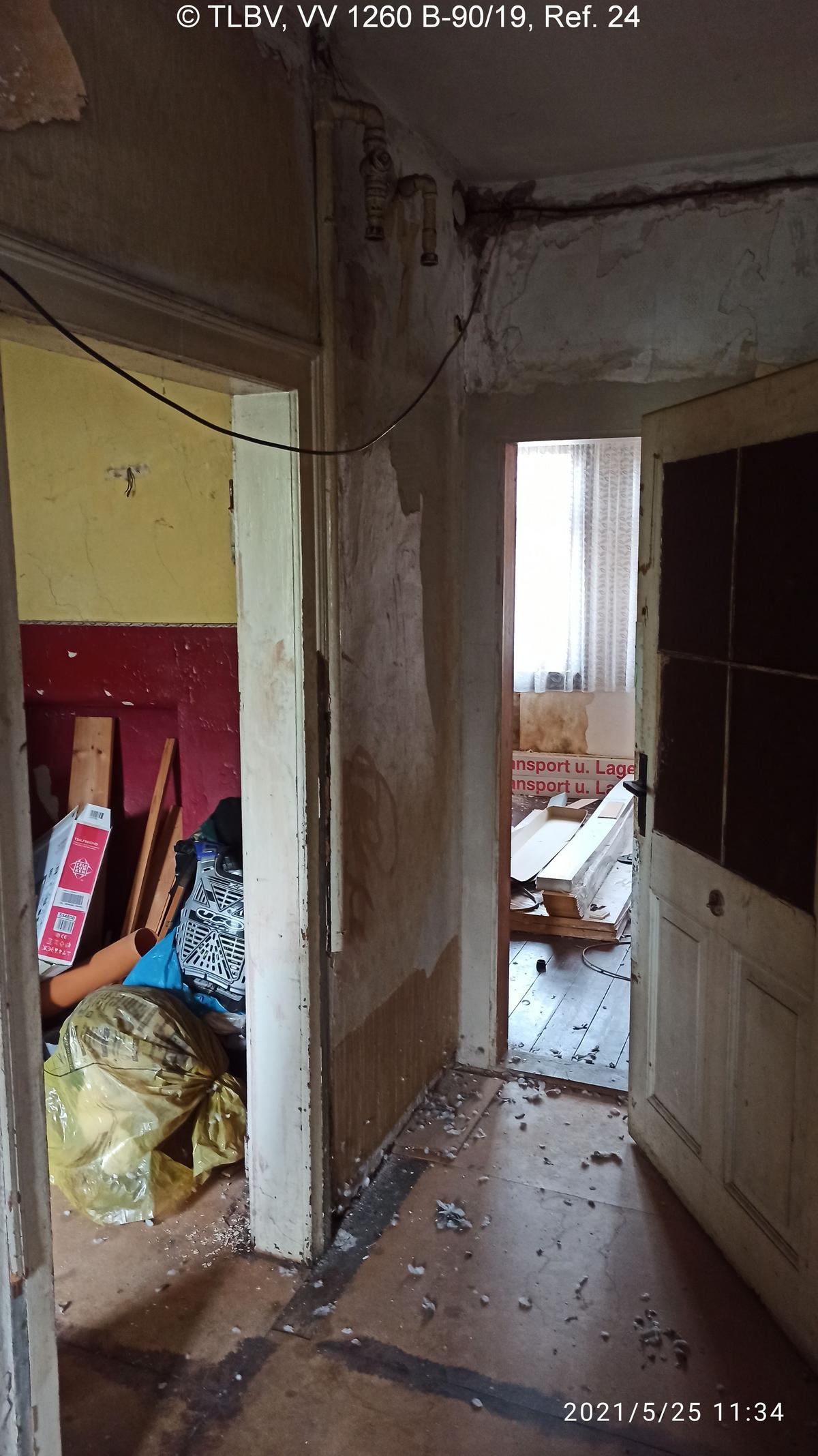 Flur mit Blick in zwei Zimmer, alles vermüllt, Taubenkot; Wandanstrich/Tapeten/Fußboden zerstört, Elektrokabel freihängend, Innentür stark verschlissen