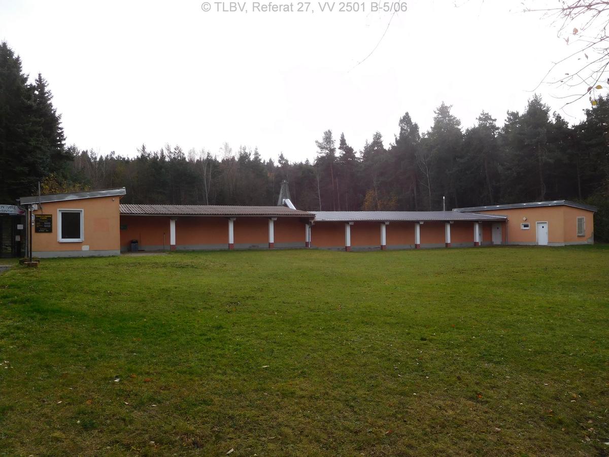 über die Wiese auf sehr langgestrecktes eingeschossiges Haus geblickt