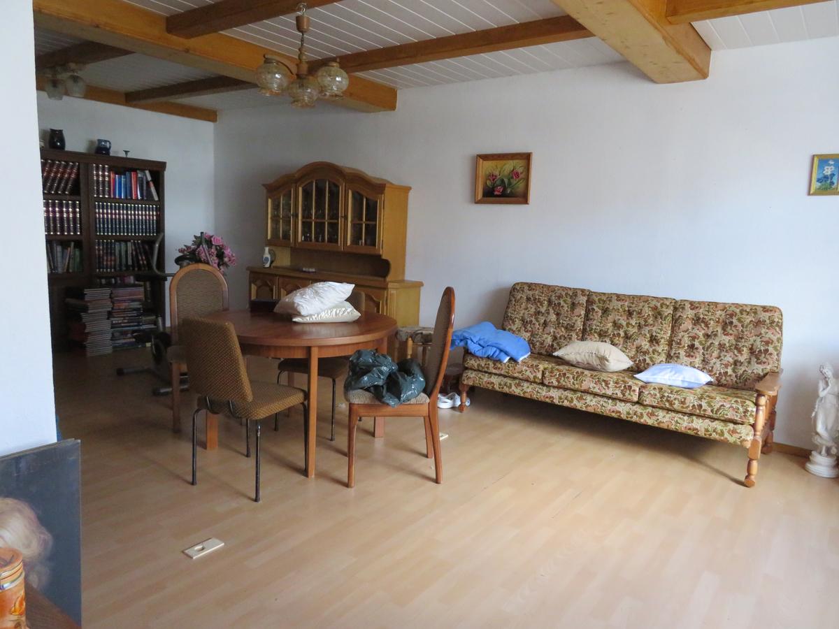 Zimmer unberäumt, Fußboden Laminat, Wände geweißt, Fachwerkdeckenbalken mit dunklerem Holz verkleidet, Zwischenräume mit Deckenpanele
