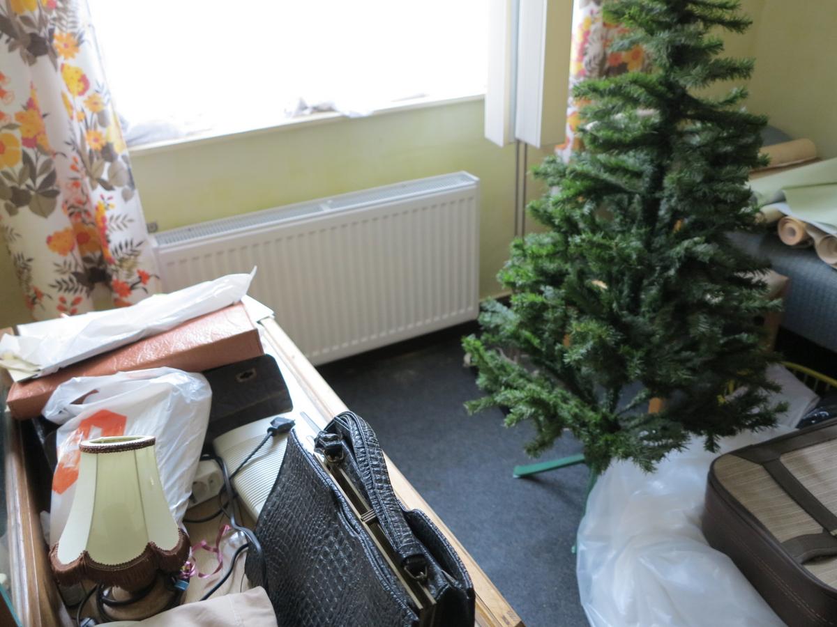 kleiner Zimmerausschnitt mit Blick auf ein Fester, darunter ein Heizkörper und verschlissener Hausrat
