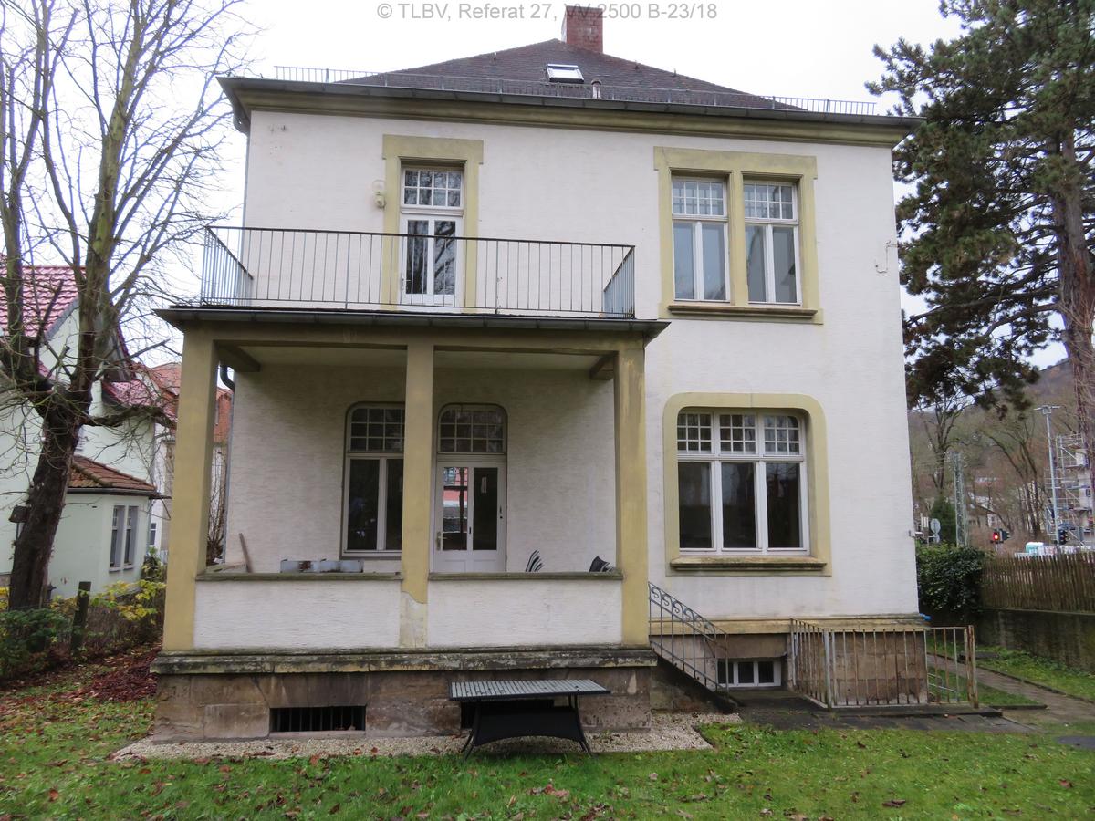 zweigeschossiges Haus mit Balkonanbau auf der linken Haushälfte, Haus weiß verputzt mit gelben Hervorhebungen um die Fenster und an den Säulen des Balkonanbaus