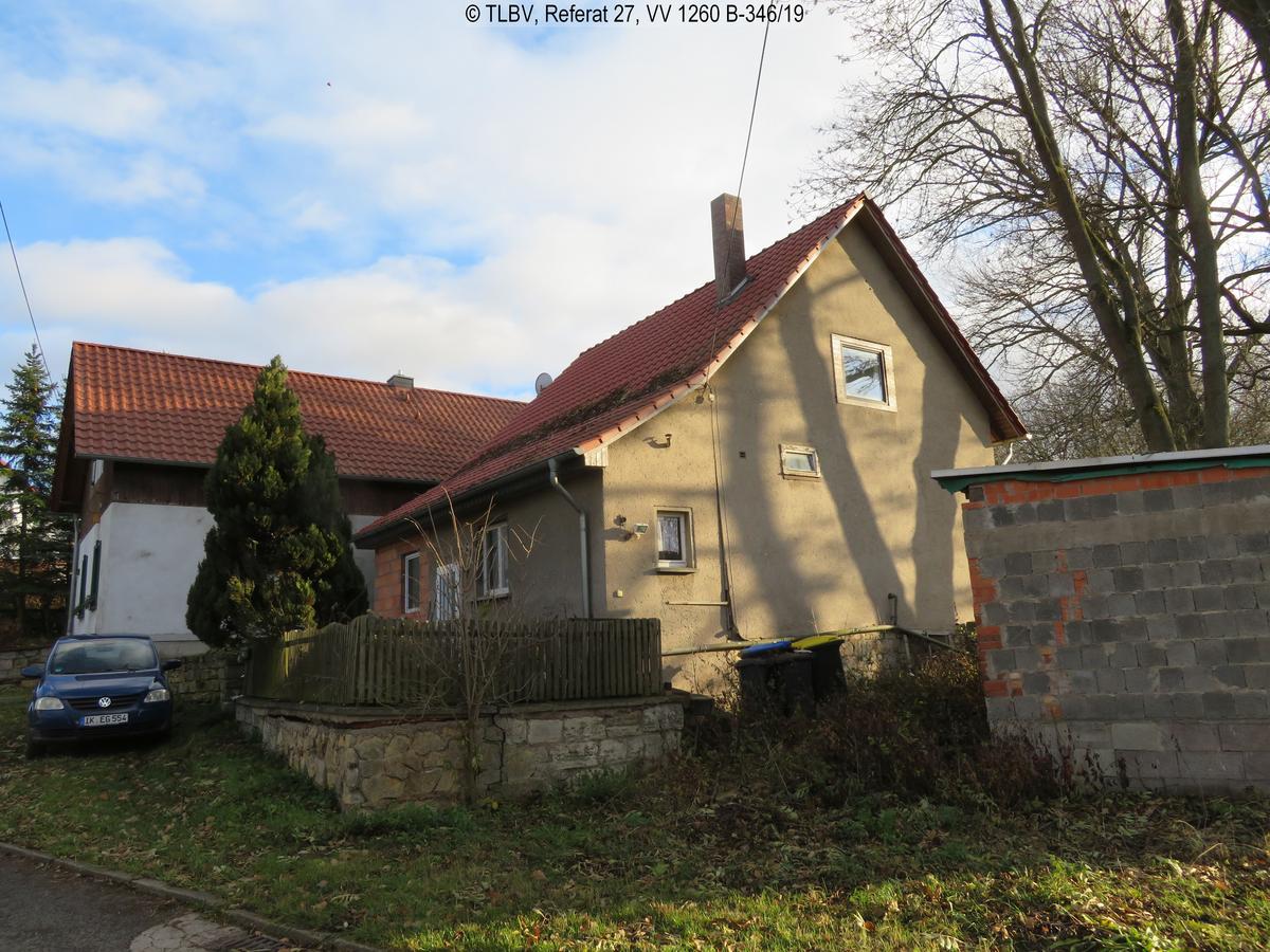 giebelseitige Ansicht eine kleineren Einfamilienhauses mit Satteldach, nur drei sehr kleine Fenster auf der Giebelseite; Haus verputzt