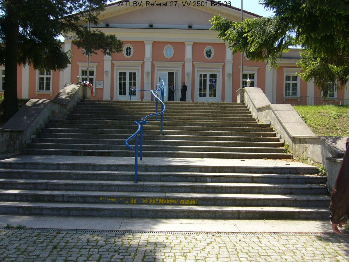 Treppenaufgang zu Haus mit theaterhafter Struktur, rosa Fassade