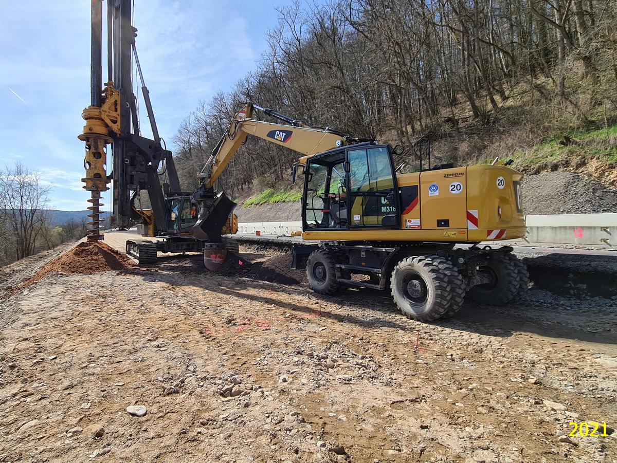 Ein Bagger arbeitet an dem Verbau der Stützwand der Brücke.