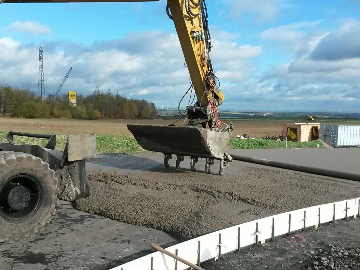 Auf dem Bild sieht man einen Bagger bei den Arbeiten am Betoneinbau.