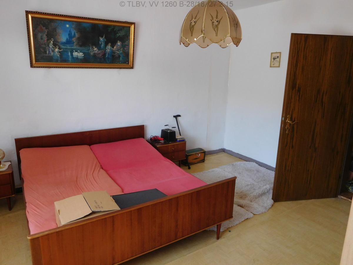 Zimmer, geweißte Wände, verzogener Linoleumfußboden, karg möbliert
