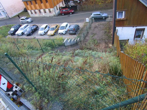 unbebautes, umzäuntes Grundstück, Ansicht vom Grundstücksende auf die Straße