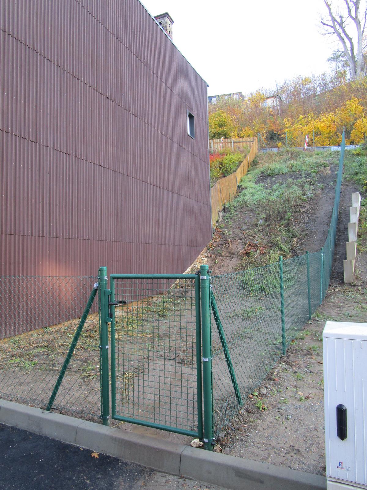 unbebautes, eingezäuntes Grundstück in Hanglage, Blick von der Straße