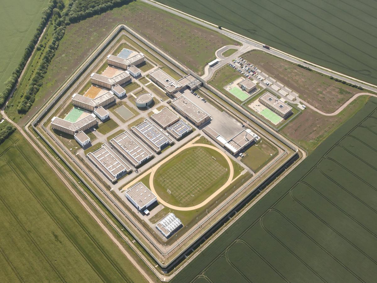 Luftbildaufnahme aus gegengesetzter Himmelsrichtung. Der Sportplatz ist noch deutlicher zu erkennen. Dieses Mal ist das Foto etwas näher aufgenommen worden. Man kann die Anzahl der Gebäude mit ihren Flachdächern klar erkennen.