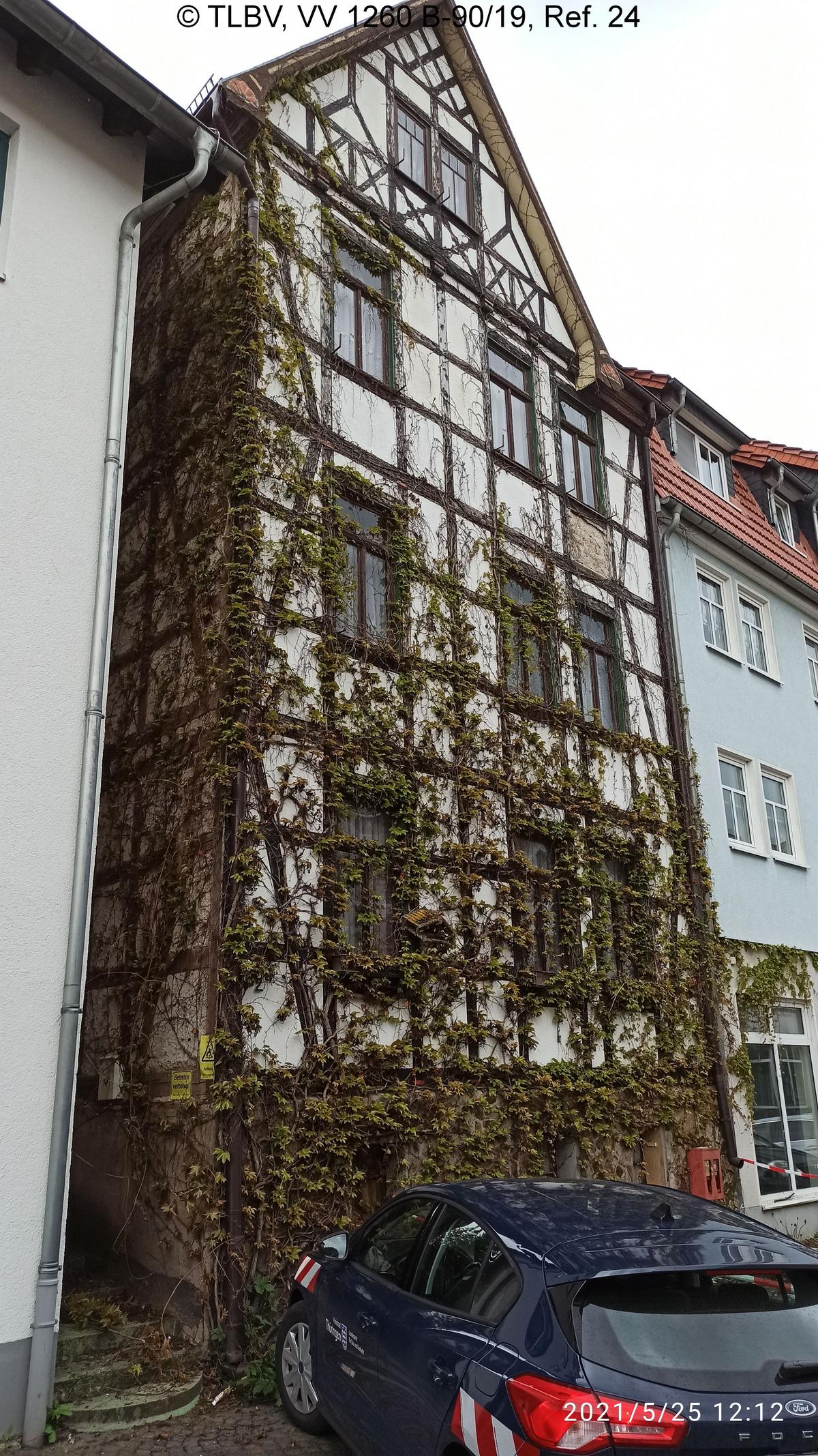 Fachwerkfassade mit Efeu berankt, davor parkende PKW, schmale Gasse trennt linksseitig das Nachbarhaus ab, rechtsseitig mit Nachbarhaus verbunden