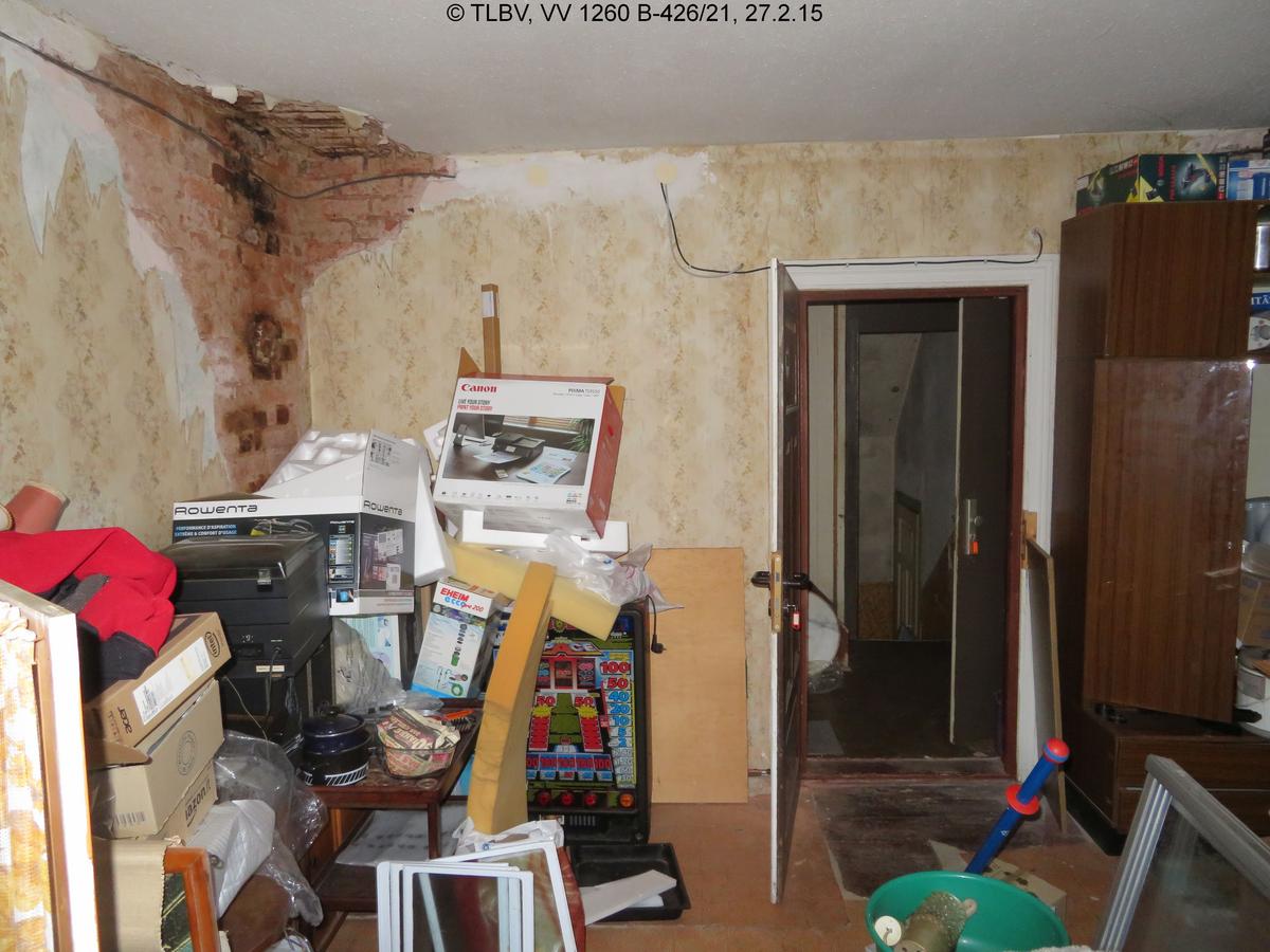 vermüllter Raum im DG mit Feuchtigkeitsschäden an Zimmerecke/Decke