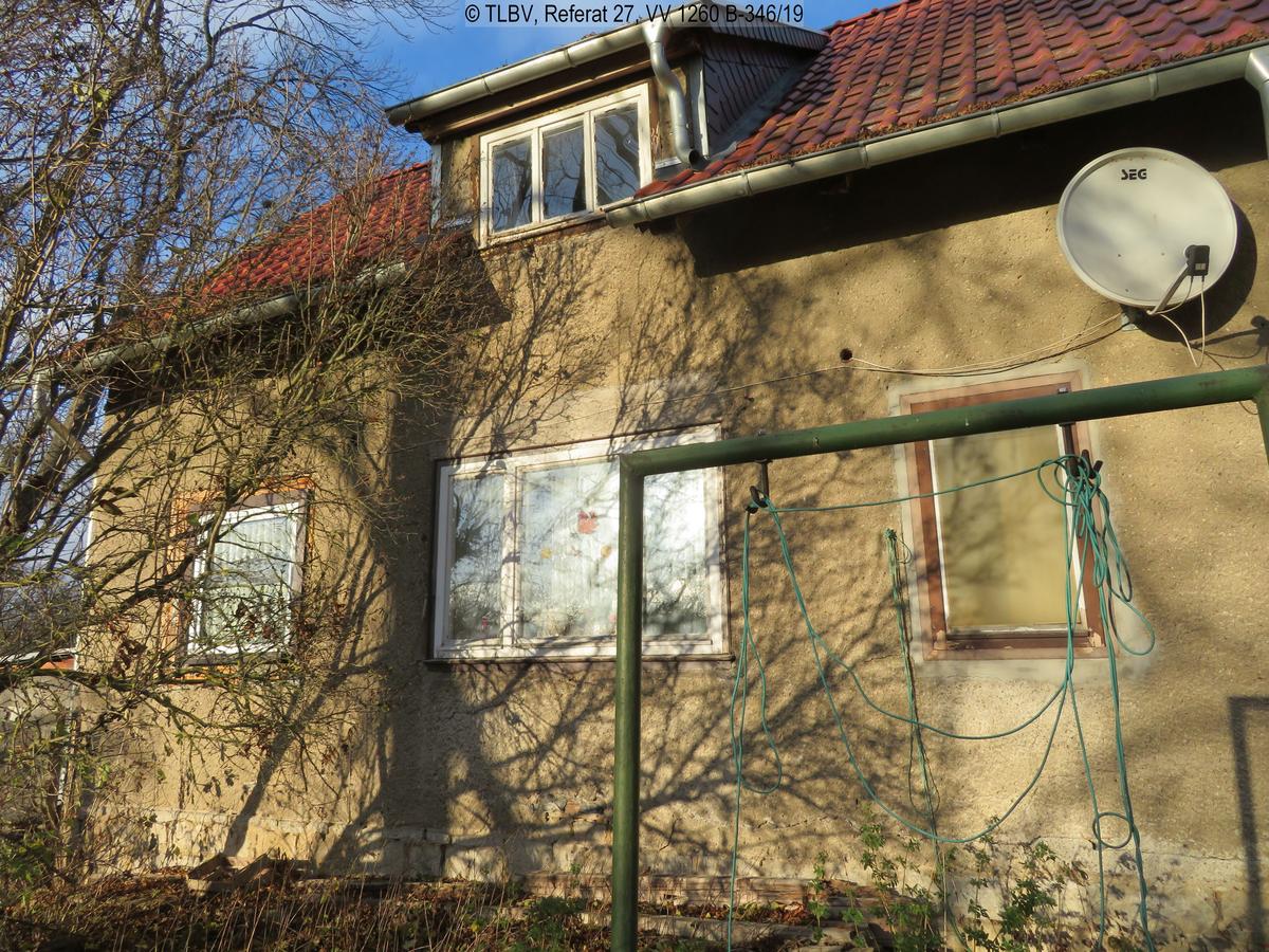 Blick durch jahreszeitlich bedingt laublose Bäume auf eingeschossiges EFH mit Gaube; Wäscheplatz, drei Fenster im EG