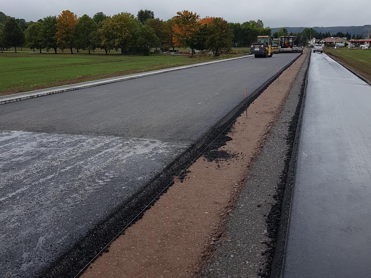 Auf dem Foto erkennt man den Einbau der Asphaltbinderschicht mittels Asphaltfertiger.