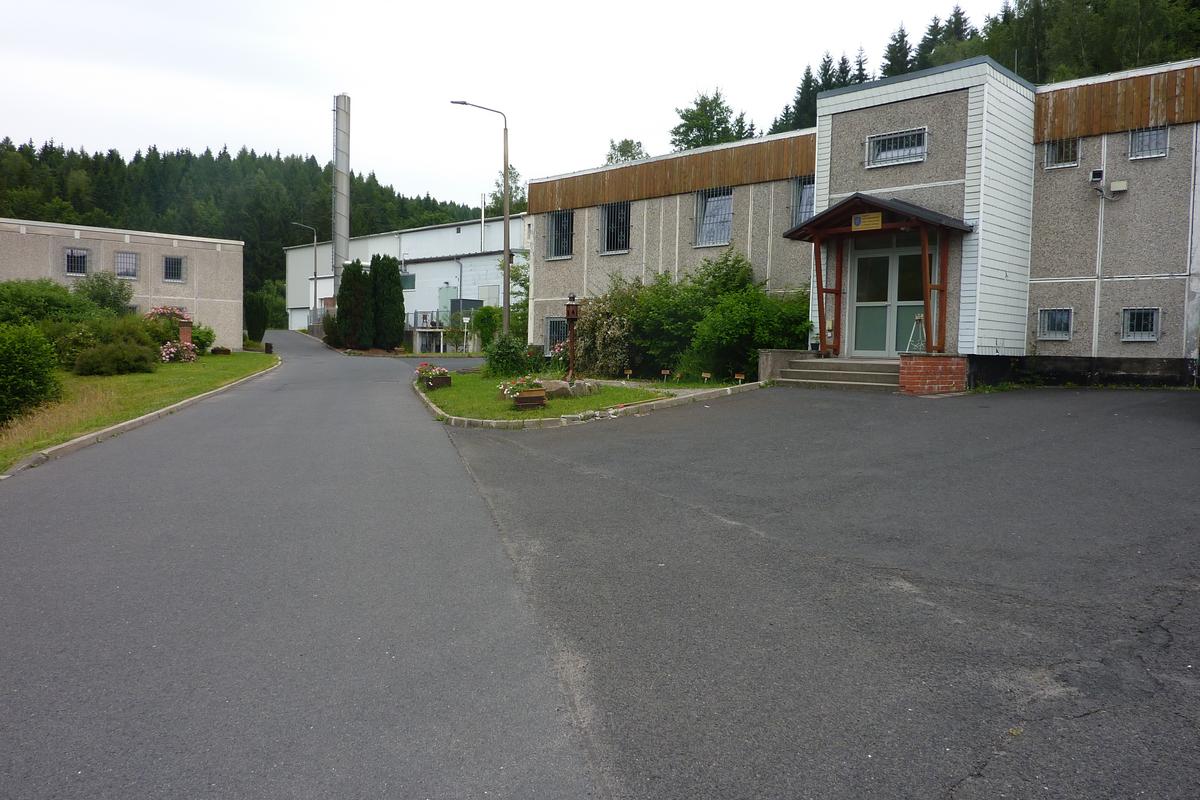 Auf dem Bild sind drei zweistöckige Gebäude zu erkennen. Dazwischen befinden sich asphaltierte Straßen, die von Rasenflächen umgeben sind.