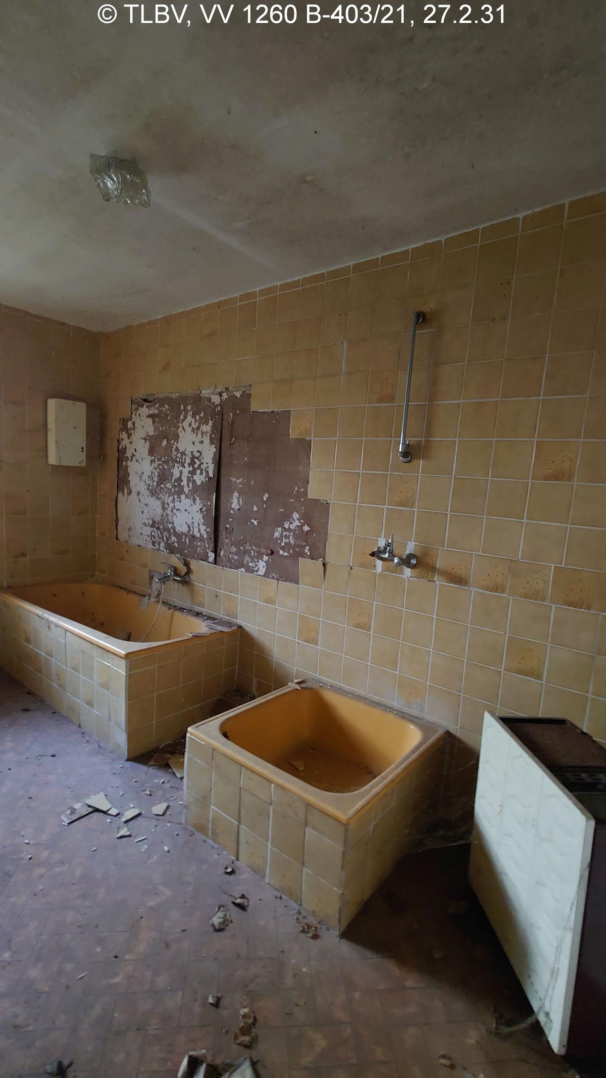 Bad mit Wanne und Dusche ohne Duschkabine, orange Fliesen fallen teilw. von der Wand, Armaturen zerstört; alles verschmutzt