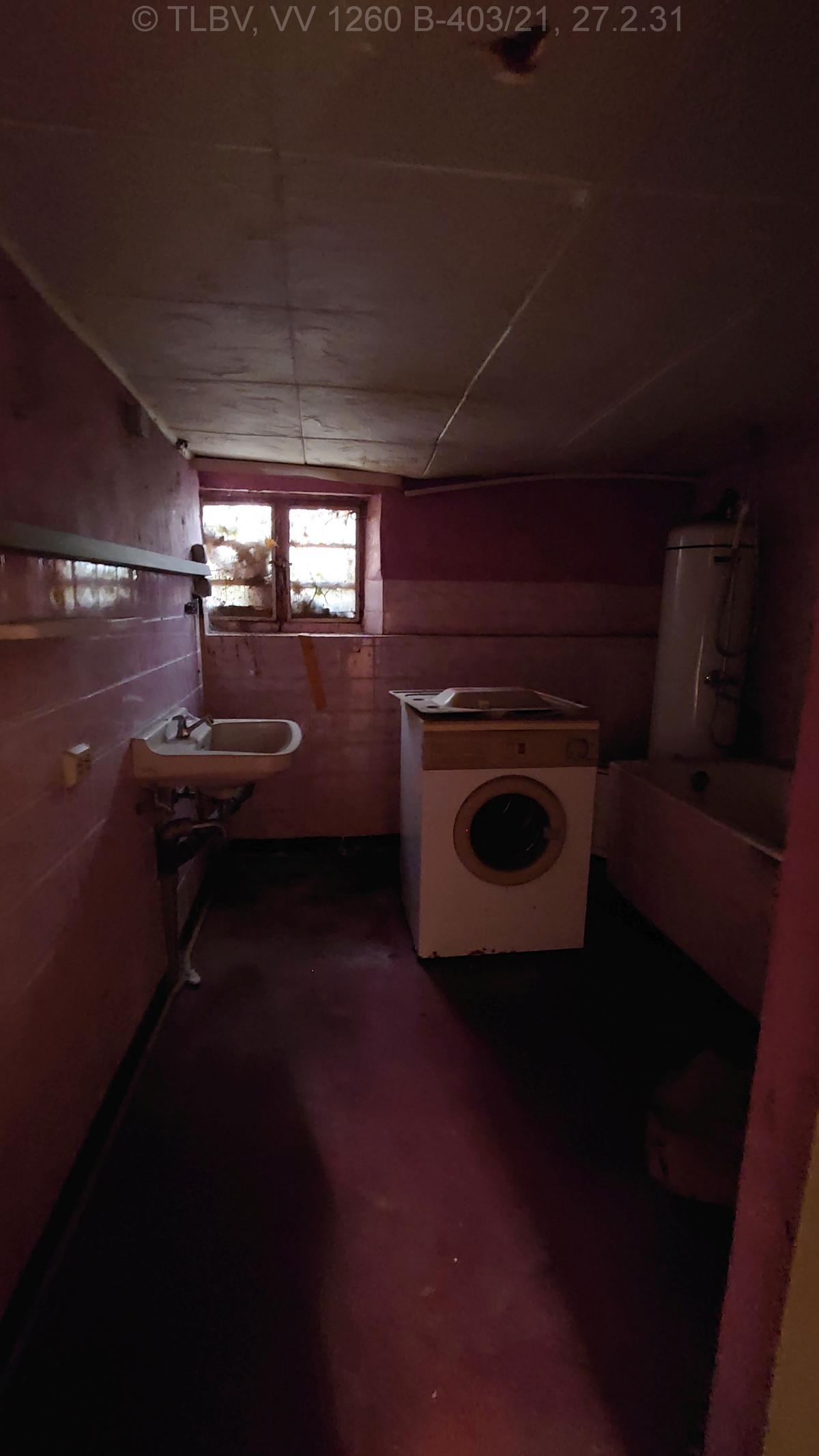 langes dunkles Bad mit sehr kleinem Fenster und niedriger Decke, Badeofen, Badewanne und Waschbecken; Zimmerdecke hängt durch