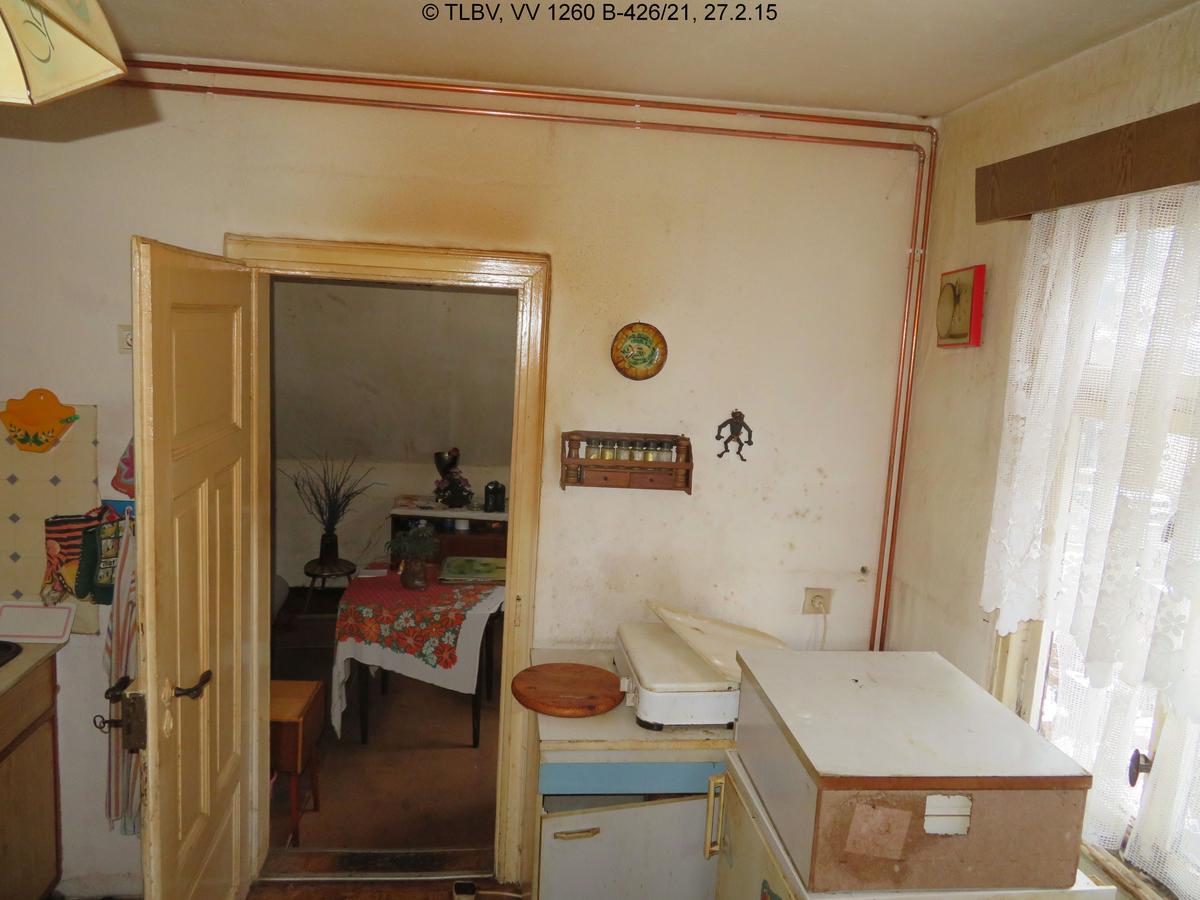 Blick durch unberäumte Küch in Zimmer; Holztür weiß lackiert, jedoch stark verschmutz; Kupferrohre über Putz verlegt