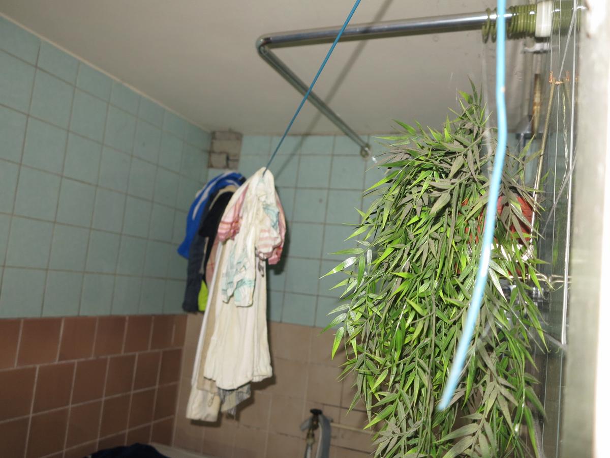 raumhoch gefliestes, verschmutztes Bad; Wäscheleine mit alter Wäsche quer durchs Bad gespannt; Bad ohne Fenster