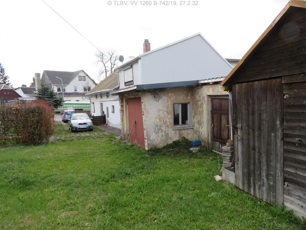 Blick von der Wiese entlang der Garage zum Wohnhaus