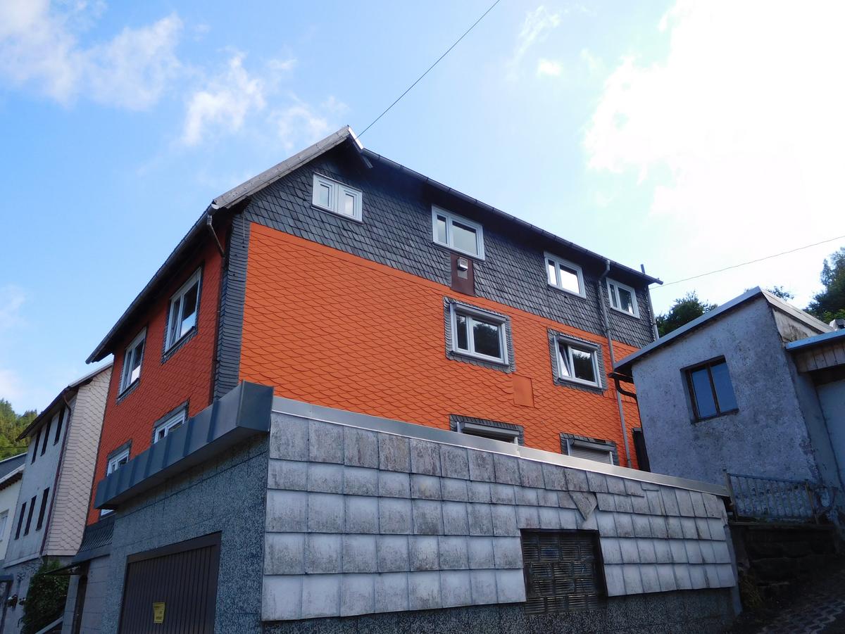 im Vordergrund die Garage, dahinter eine Eckansicht des Hauses am Hang, EG, 2 OGs und DG