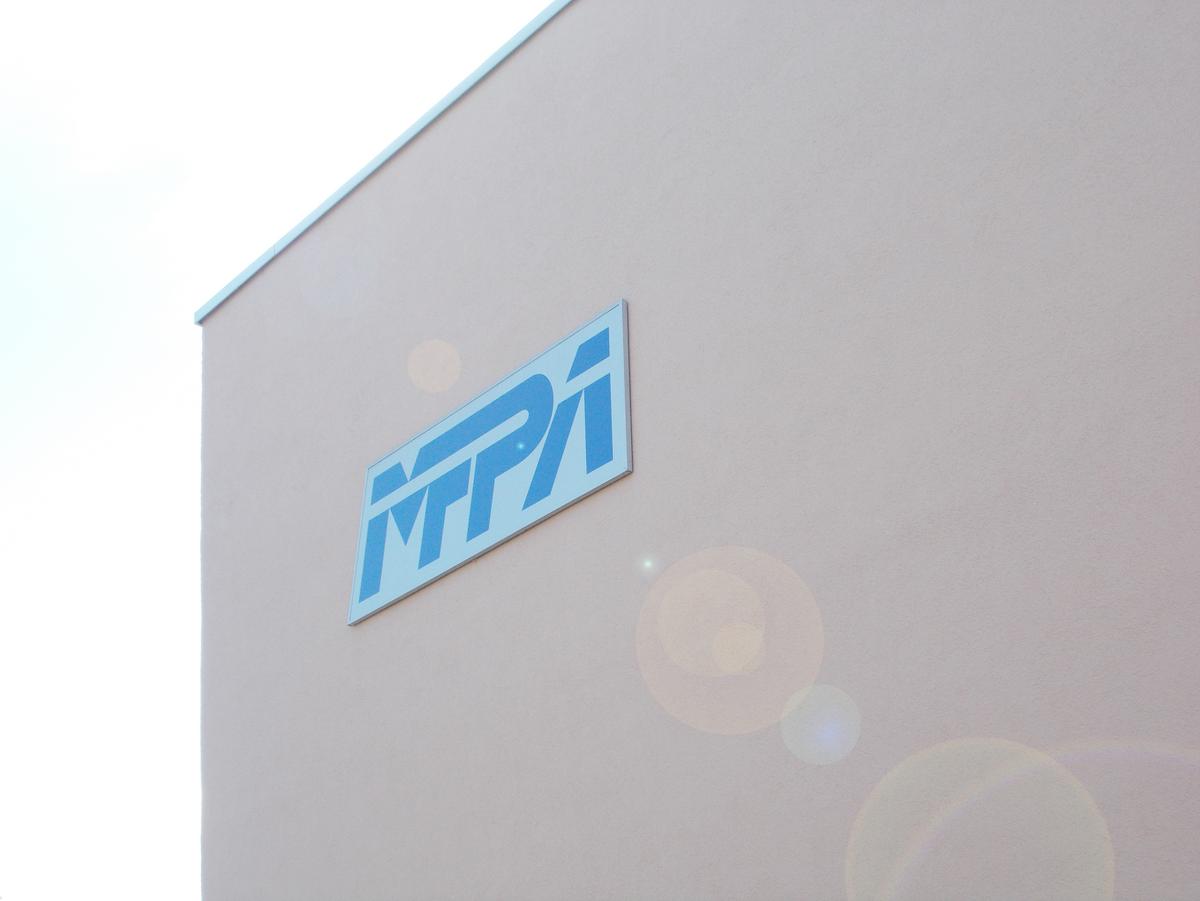 Detailfoto der Fassade, die dreiviertel des Fotos einnimmt. Ein Schild mit dem Logo der MFPA hebt sich vor dem braunen Putz hervor.