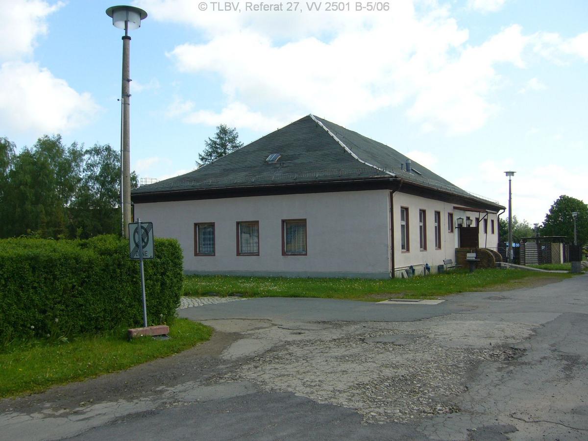 eingeschossiges Gebäude mit Walmdach; Ansichtsseite mit drei Fenstern, seitlich weitere Fenster und Hauseingang