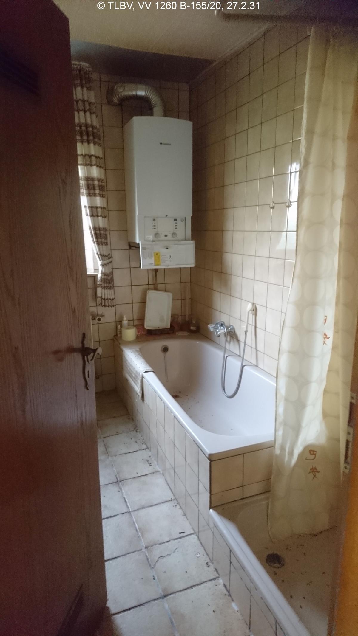 gefliestes Bad mit Badewanne und Dusche, sowie Heiztherme, Fliesen modernisierungsbedürftig