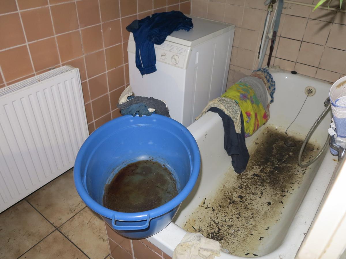 Badewanne in kleinem, gefliestem Bad; alles sehr stark verschmutzt