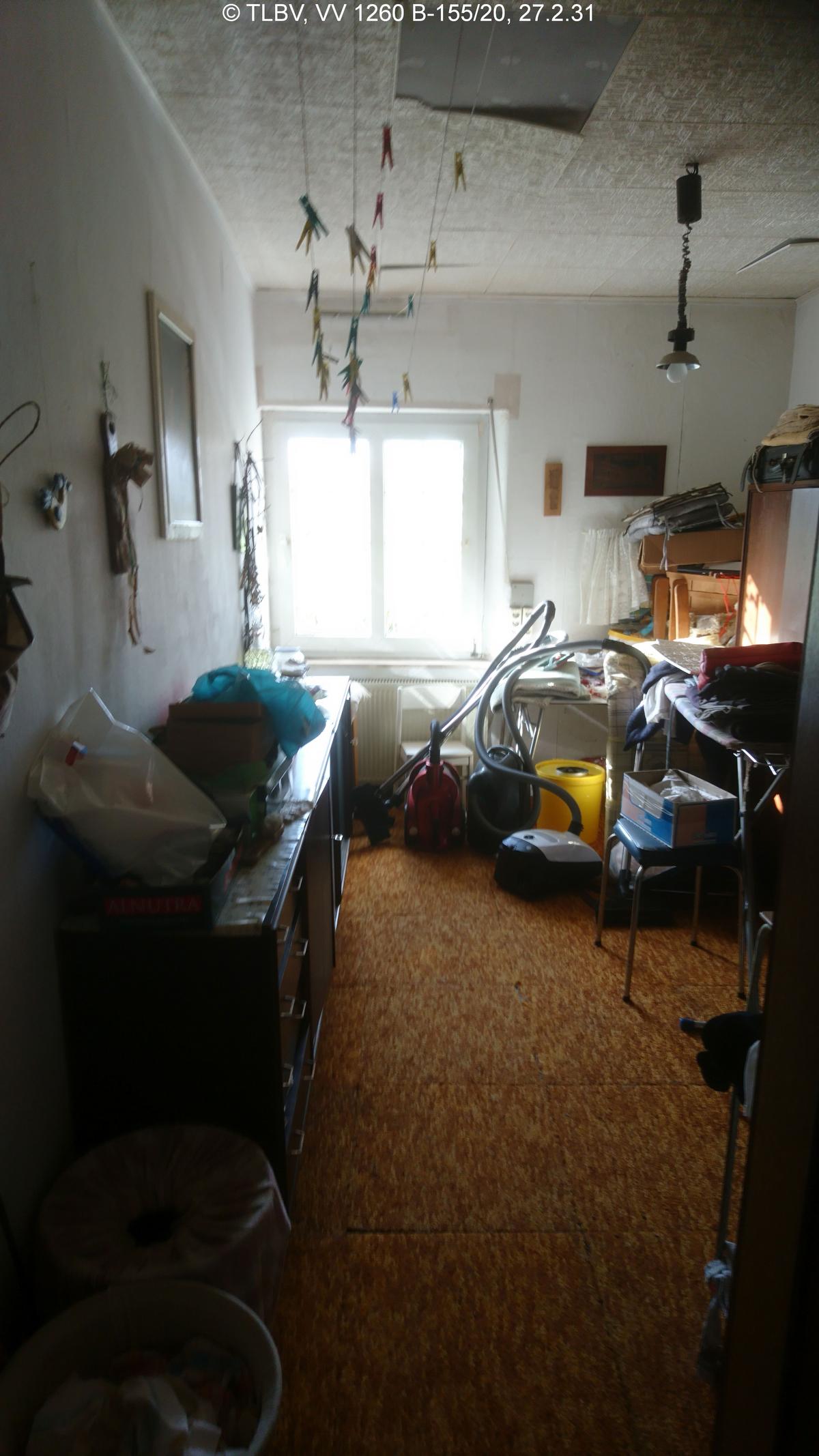 schmales Zimmer mit Fenster, unberäumt, Fußboden mit Teppichplatten, Decke mit Deckenplatten aus Styropor, tlw. abgängig