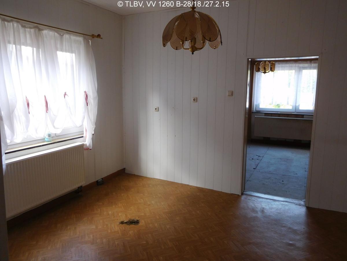 Durchgangszimmer mit Fenster, verschlissener Fußboden und Wandanstrich